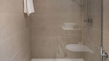 A modern shower area with a glass door, a white bathtub, and a towel rack.