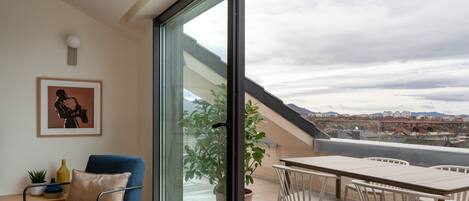A modern living room with a large sliding glass door leading to an outdoor terrace.