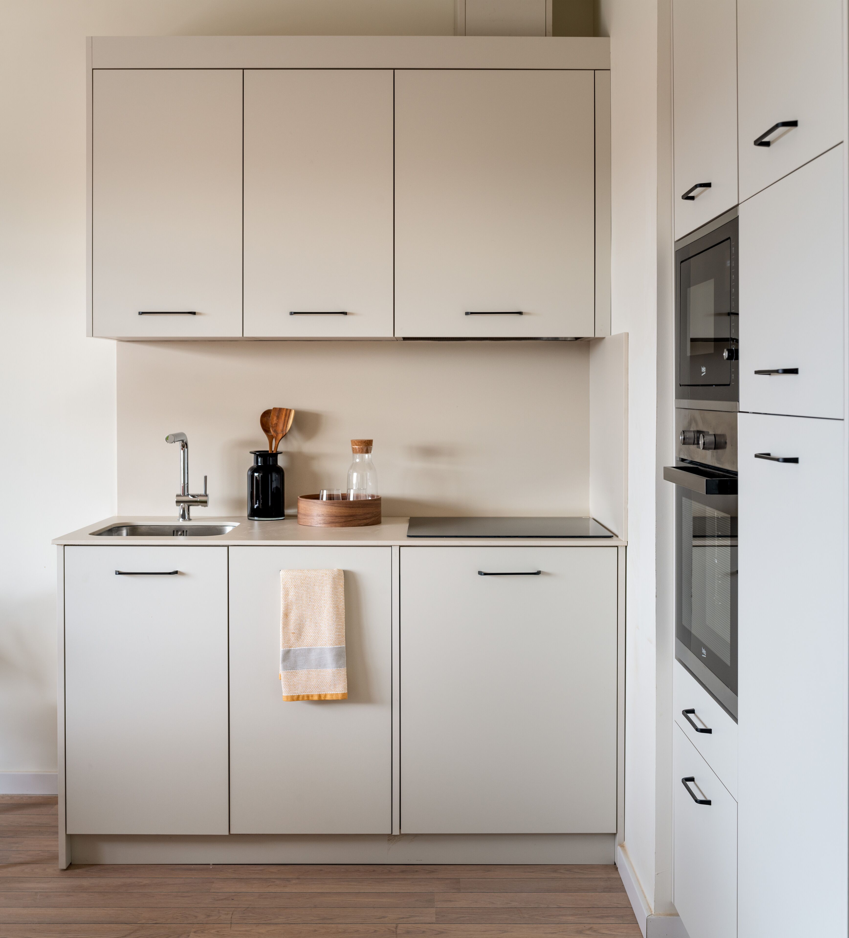 Een moderne keuken met witte kasten, een roestvrijstalen spoelbak en een ingebouwde oven.