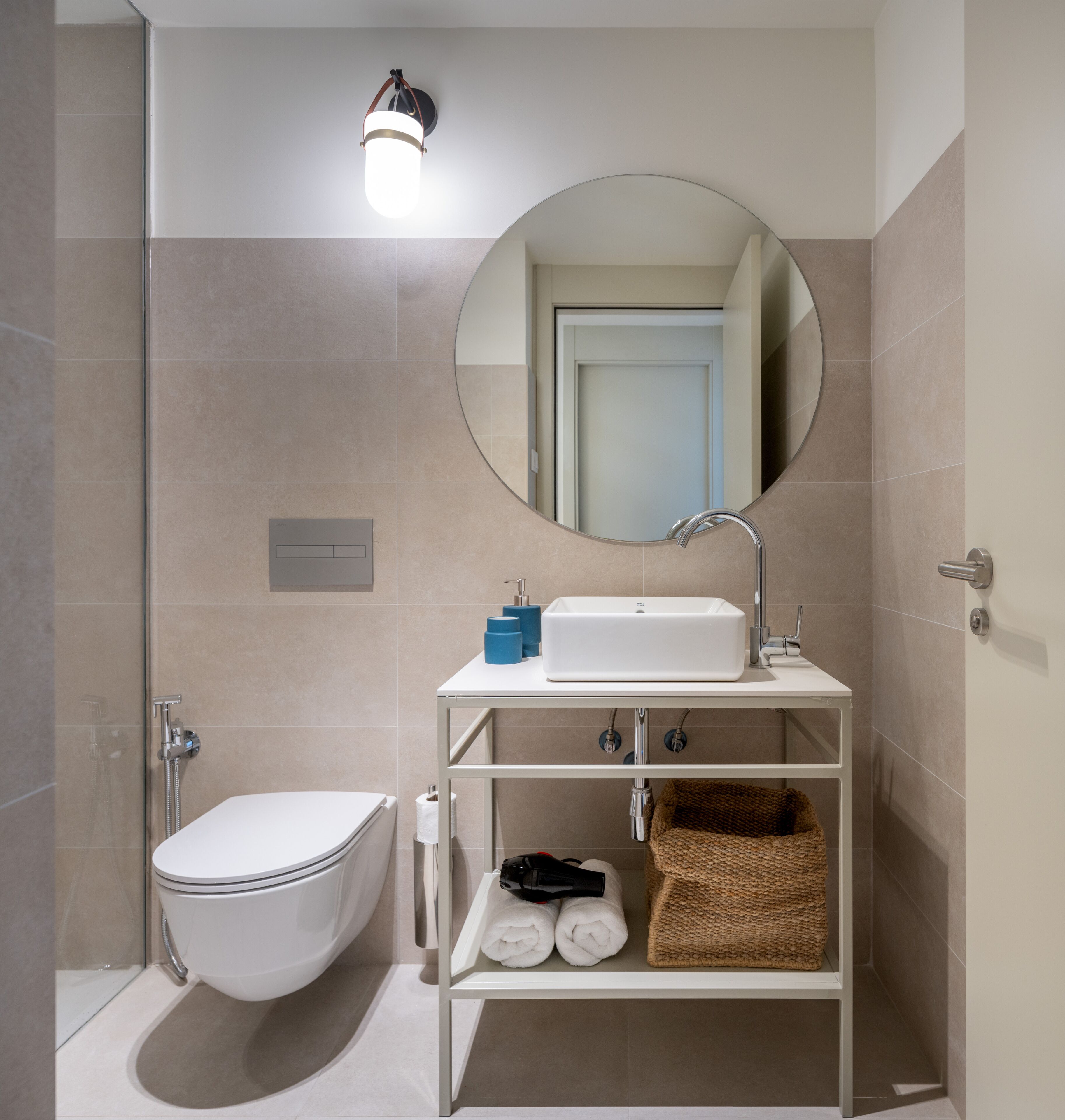 Une salle de bain moderne équipée de toilettes, d’un lavabo et d’une douche. Un miroir est placé au-dessus du lavabo et un porte-serviettes en dessous.