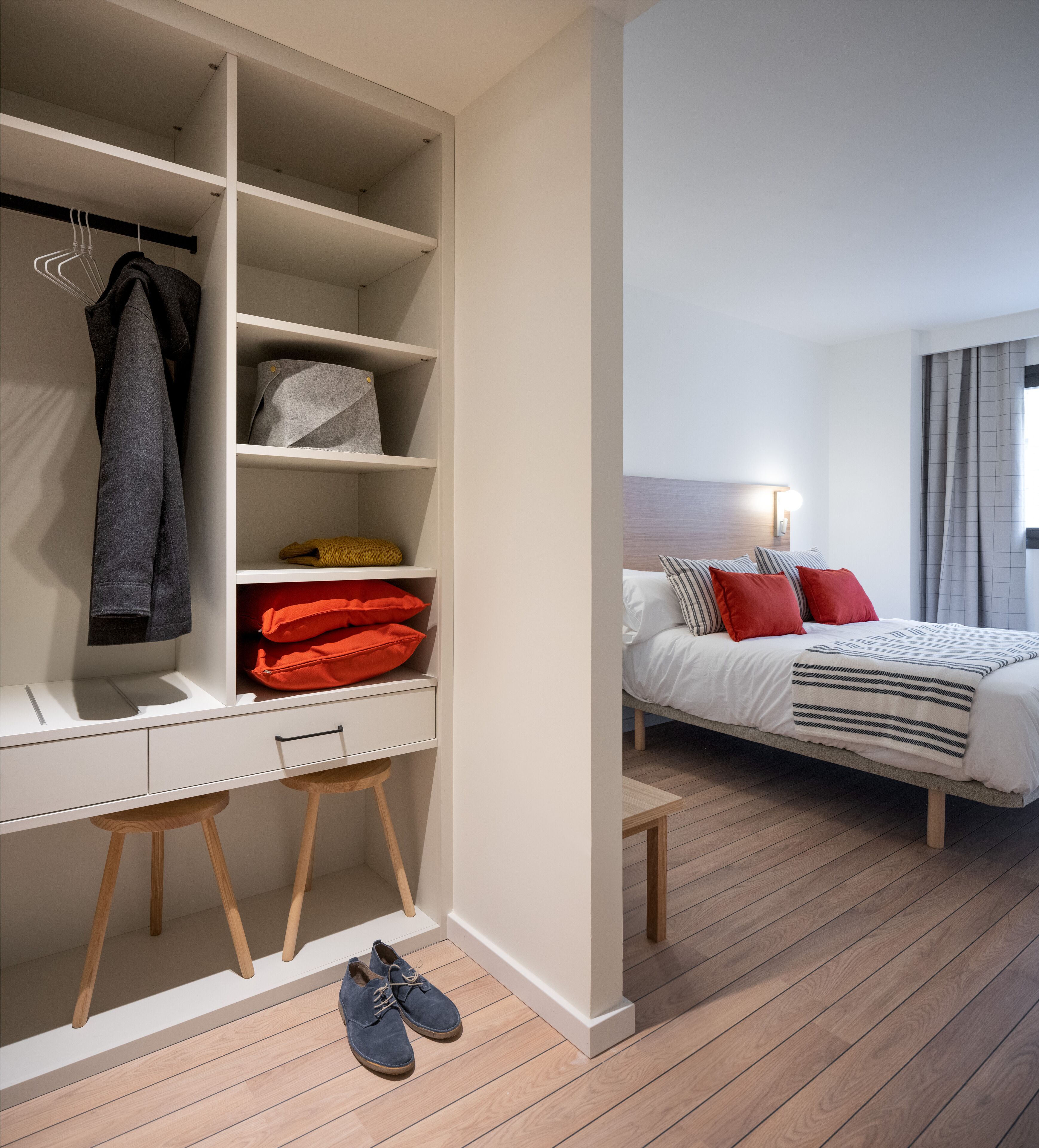 A bedroom with a bed, bedside table, and a wardrobe with shelves.