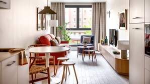 A modern apartment with a dining area, a sofa, a TV, and a view of the city. - Aparthotel Libere Vitoria (Vitoria-Gasteiz)