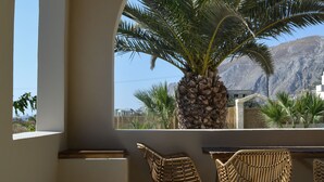 A terrace with a view of mountains, featuring two wicker chairs and a table.