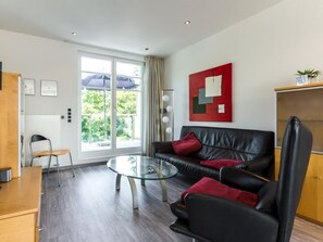 A modern living room with a glass coffee table, leather sofa, and a red abstract painting.