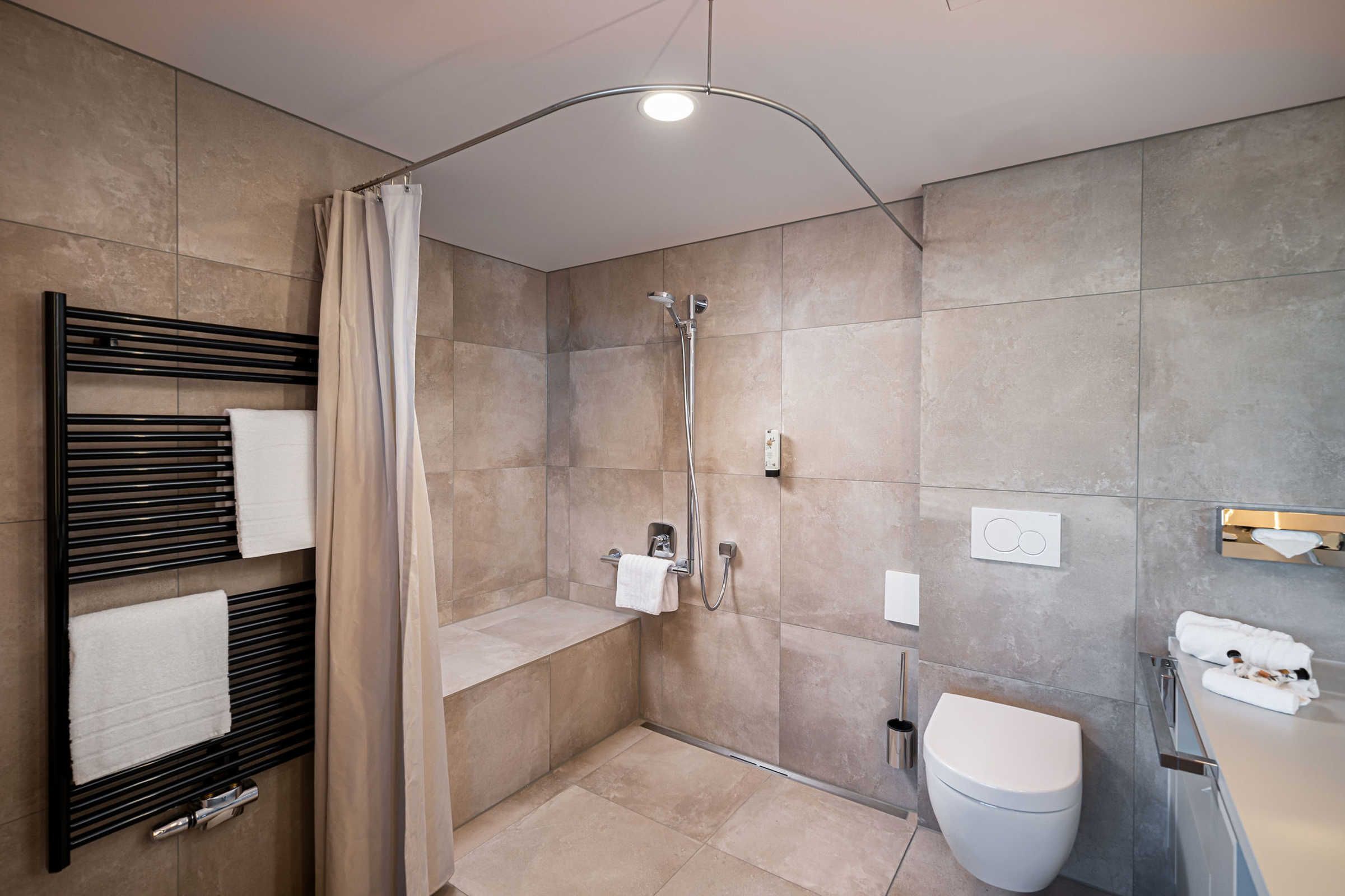 A modern bathroom with a shower, toilet, and towel rack.