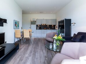 Ein modernes Wohnzimmer mit einem Glastisch, einer Couch und einem Essbereich mit Stühlen.