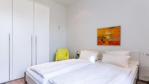 Ein Schlafzimmer mit einem großen Bett, einem Kleiderschrank, einem Sessel und einem Bild an der Wand.