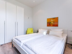 Ein Schlafzimmer mit einem großen Bett, einem Kleiderschrank, einem Sessel und einem Bild an der Wand.