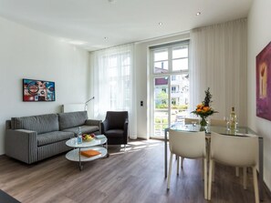 A modern living room with a sofa, armchair, coffee table, and dining table.