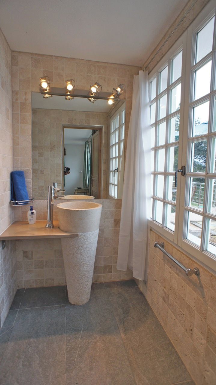 A bathroom with a large sink, a mirror, and a window.
