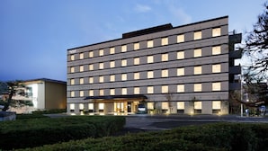 Een modern hotel met een symmetrische gevel, veel ramen en een goed verlichte ingang.