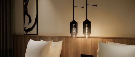 A hotel room with a wooden headboard, two bedside lamps, and a wall-mounted control panel.