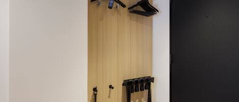 A wardrobe with a wooden panel design, a black door, and a black hanger rack.