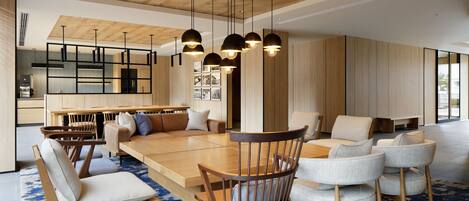 A modern dining area with wooden furniture, pendant lighting, and a large rug.