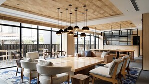Een ruime eetruimte met een lange houten tafel, meerdere stoelen en hanglampen.
