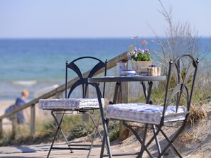 Una mesa junto a la playa con sillas, una planta en maceta y una mesita.
