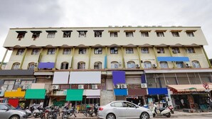 A multi-story building with several ground-level shops and a parking area. - Hotel Govindam by Sky Stays (Ahmedabad)