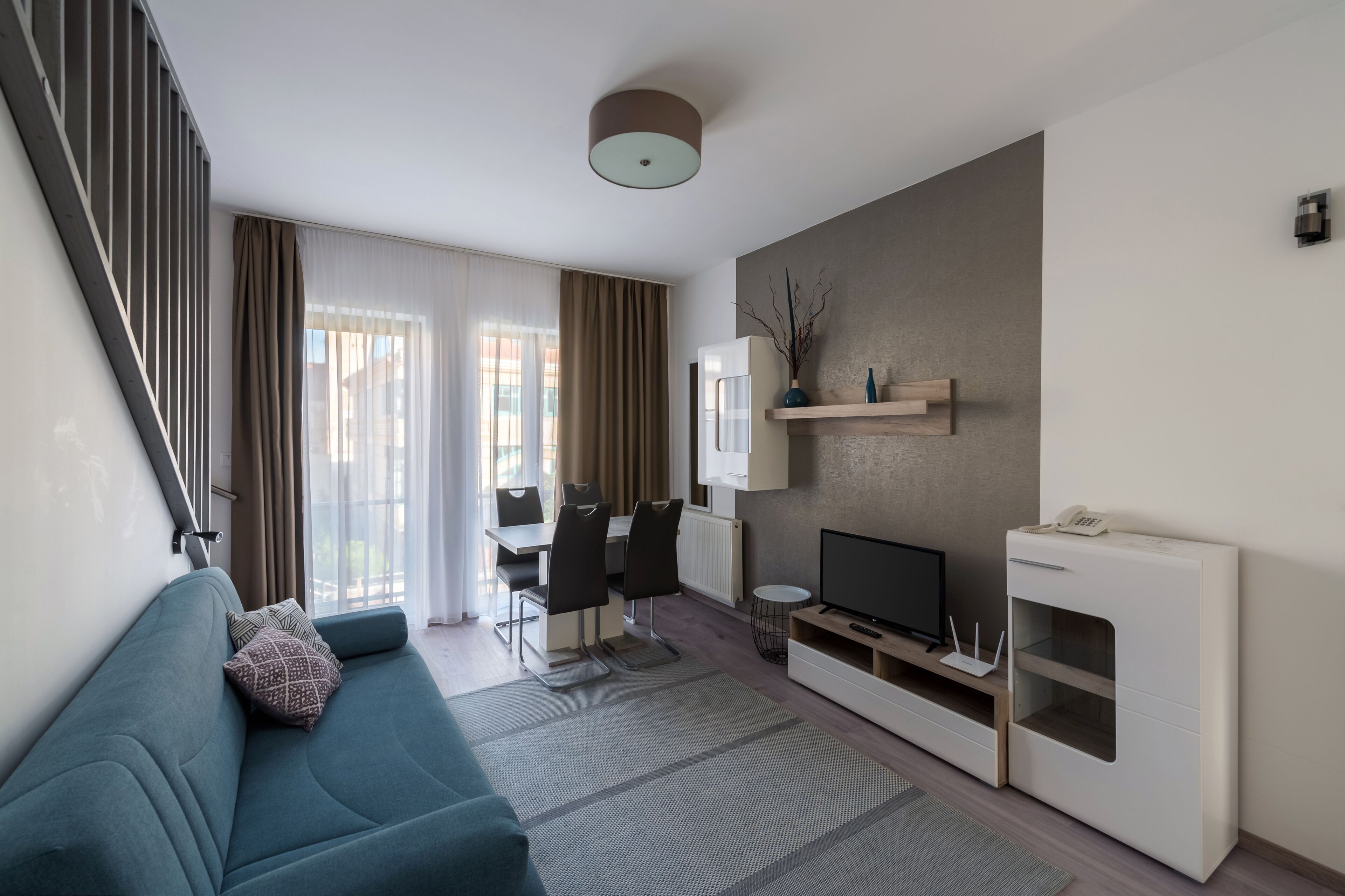 Un salon moderne comprenant un canapé, un téléviseur et un coin repas avec des chaises et une table.