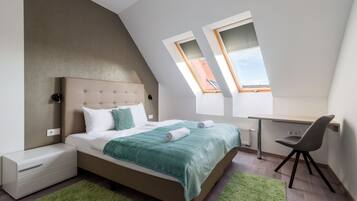 Un dormitorio moderno con cama, escritorio y dos tragaluces.