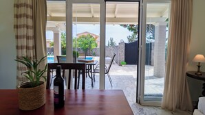 A room with a dining table, chairs, a potted plant, and a bottle of wine.