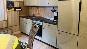 Una cocina compacta con armarios de madera, un lavamanos de acero inoxidable y un horno empotrado.