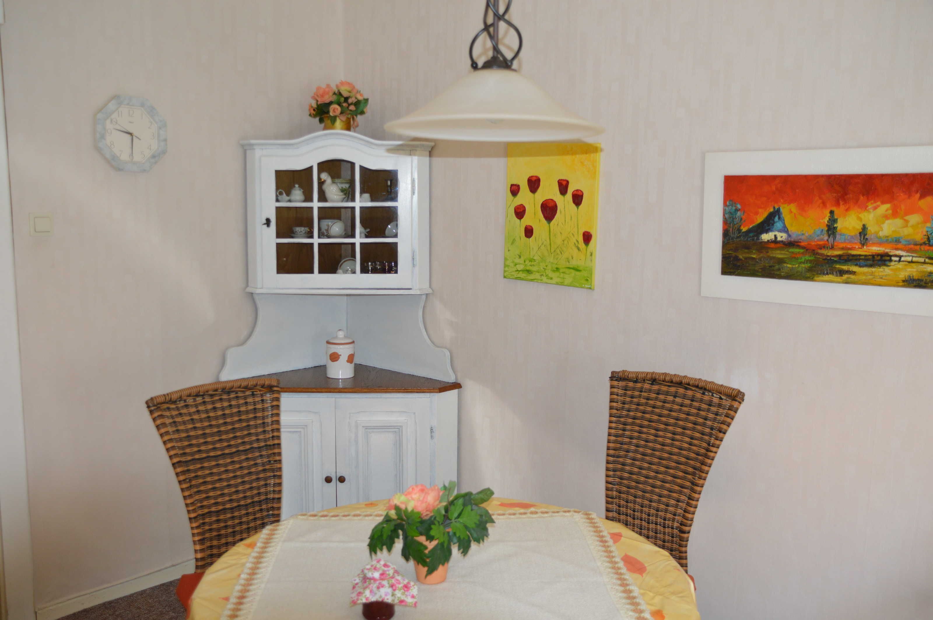 Un comedor con una mesa, sillas, un armario y adornos en la pared.