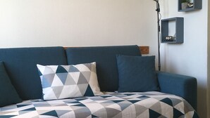 Un salon moderne avec un canapé bleu, une table basse blanche et un lampadaire.
