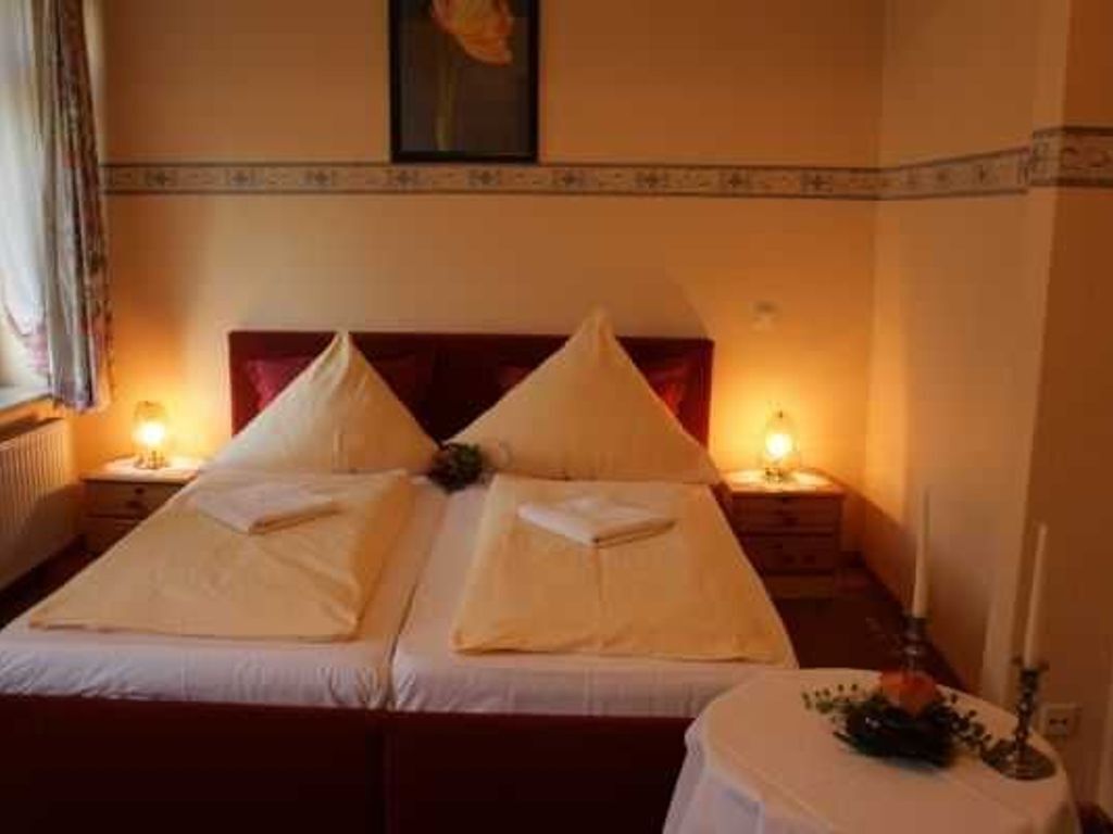 Ein Hotelzimmer mit zwei Betten, einem runden Tisch mit Kerze und einem Bild an der Wand.
