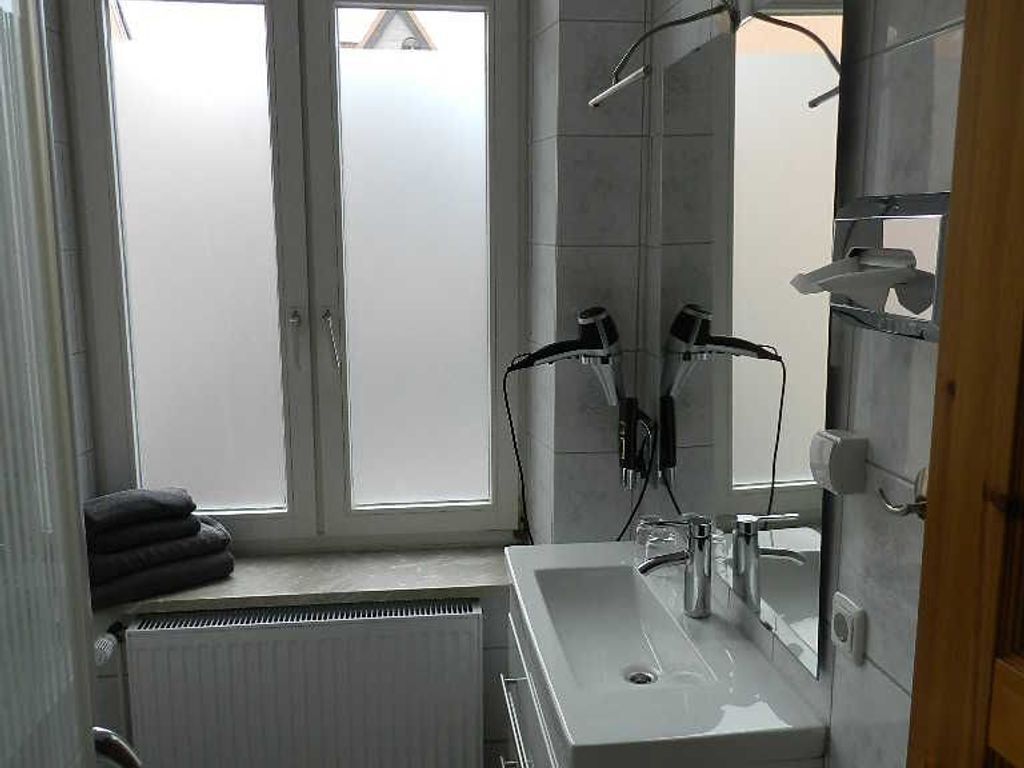 Ein modernes Badezimmer mit einem großen Fenster, einem weißen Waschbecken und einem Handtuchhalter.
