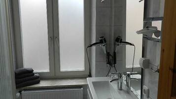 Ein modernes Badezimmer mit einem großen Fenster, einem weißen Waschbecken und einem Handtuchhalter.