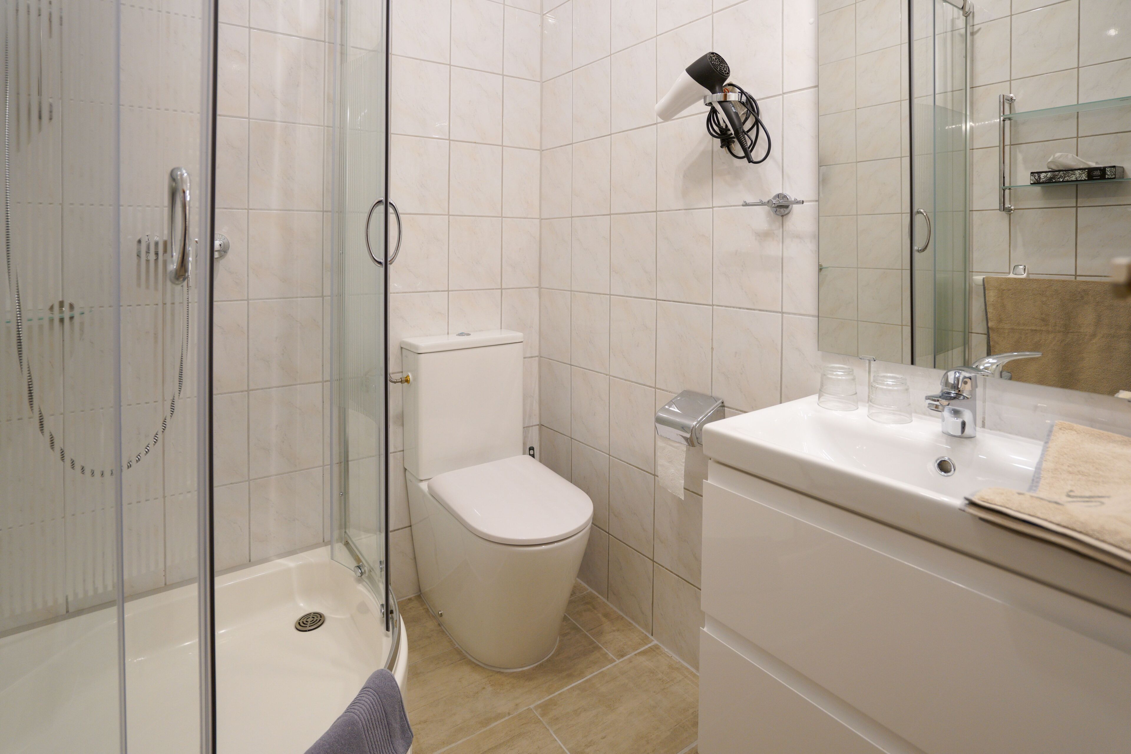 Ein modernes Badezimmer mit einer Duschkabine, einer Toilette und einem Waschbecken mit Spiegel.