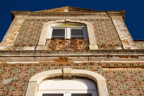 A building facade with intricate tile patterns and a window with ornate ironwork.