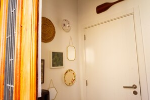 A room with a white door, a woven basket, a framed picture, and a decorative plate on the wall.