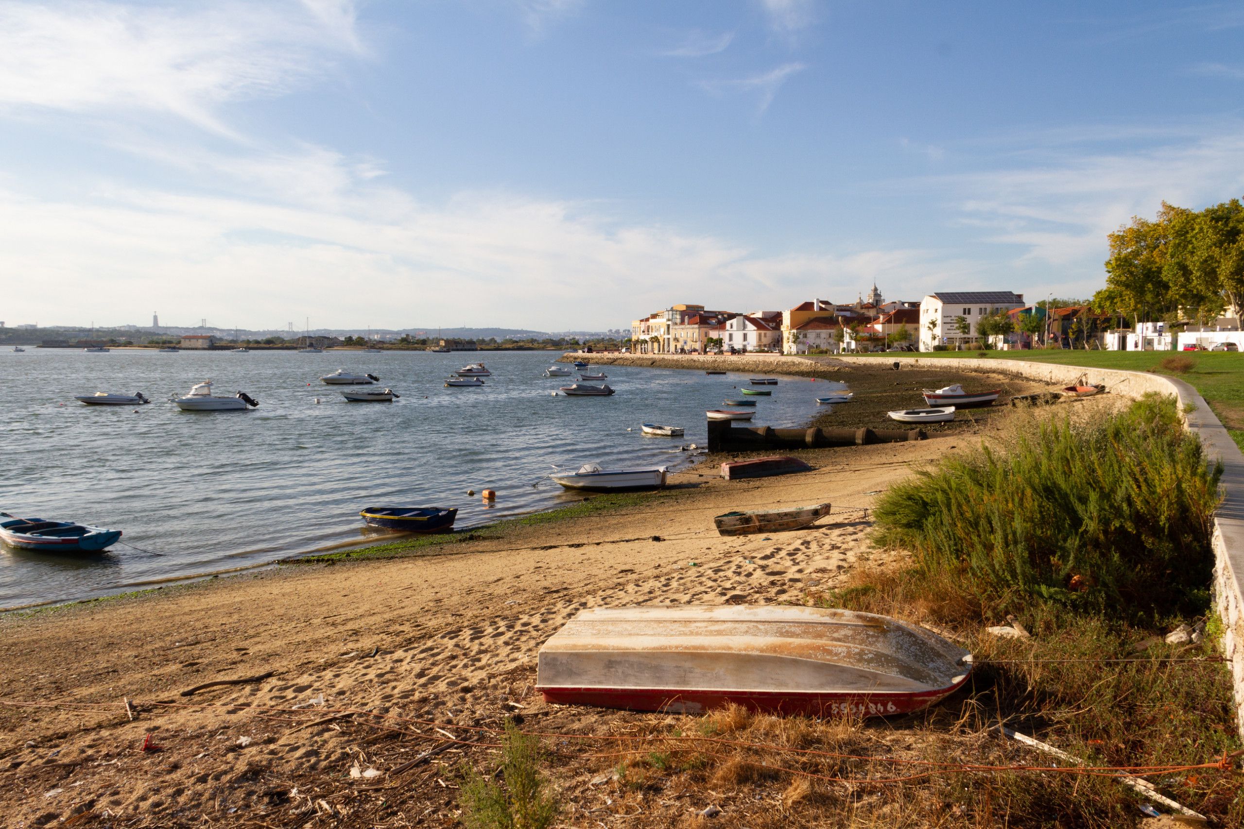 Une plage avec des bateaux, un rivage sablonneux et des bâtiments en arrière-plan.