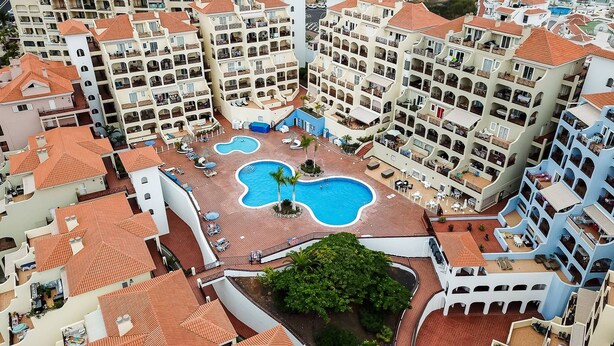 Un hôtel de grande hauteur doté de nombreux balcons, d’une piscine centrale et d’une cour aménagée.