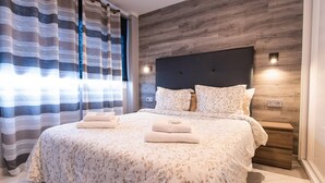 Une chambre à coucher moderne avec un grand lit, une tête de lit en bois et une table de chevet avec une lampe.