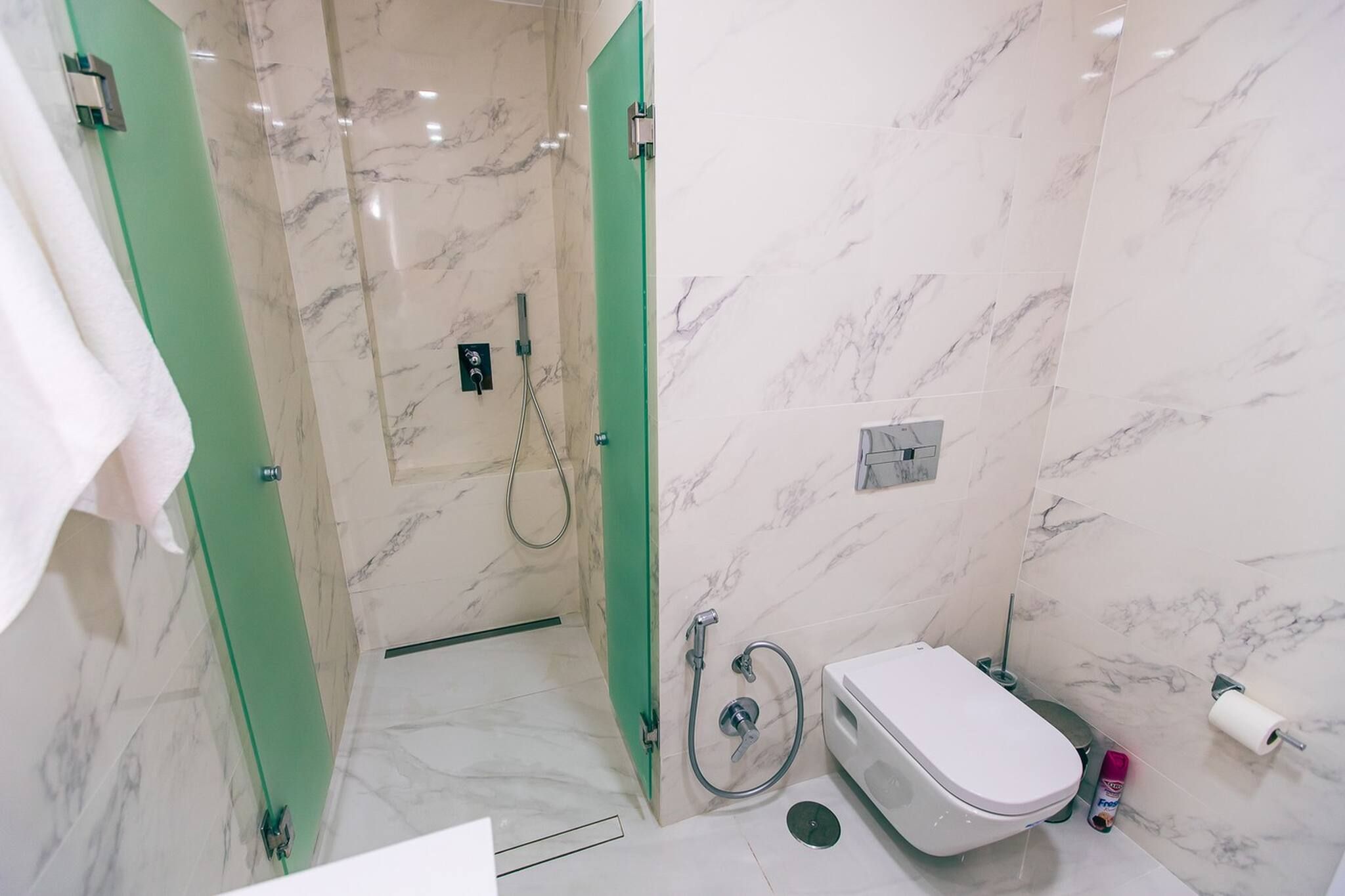 Ein Badezimmer mit Dusche, Toilette und einer grünen Tür.