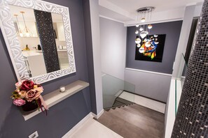 A modern bathroom with a large mirror, a glass shower enclosure, and a wall-mounted light fixture. - Luxurious 2-bedroom apartment in Los Cristianos (Arona)