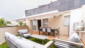 Une terrasse sur le toit aménagée avec un canapé, des chaises, une table et un espace abrité.