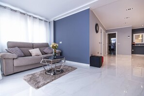 Un salon moderne avec un canapé, une table basse en verre et un vase de fleurs.