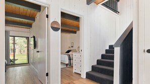 A spacious room with a wooden floor, a staircase, and a bed with a nightstand. - Condo with Parking and Smart TV! Steps to the Free Shuttle! (Mammoth Lakes)