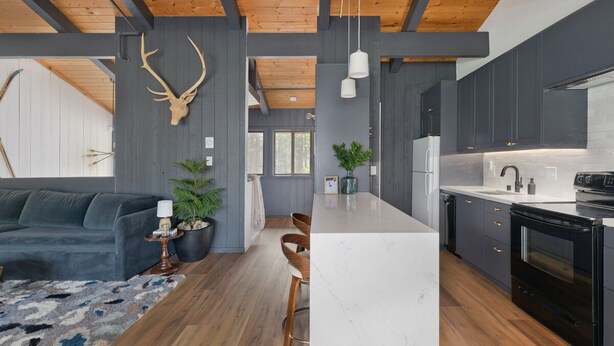 A modern kitchen with a large island, dark cabinetry, and a wooden ceiling. - Condo with Parking and Smart TV! Steps to the Free Shuttle! (Mammoth Lakes)