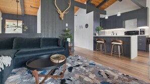 A modern living room with a dark sofa, a round coffee table, and a large antler mounted on the wall. - Condo with Parking and Smart TV! Steps to the Free Shuttle! (Mammoth Lakes)