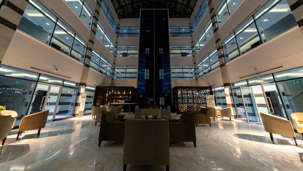 Un hall d’entrée spacieux avec un plafond haut, de nombreux espaces de détente et un bar central.