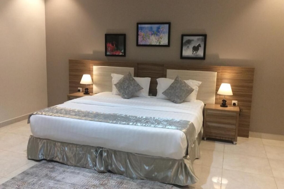 A neatly arranged bedroom with a large bed, two bedside tables, and three framed pictures on the wall.
