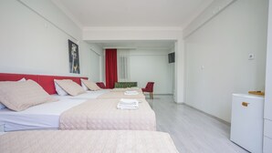 Habitación de hotel con tres camas, un escritorio, una silla y un televisor.