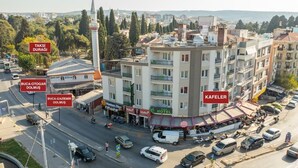 Un hotel de varios pisos con un minarete destacado, ubicado en un entorno urbano con calles y edificios visibles.