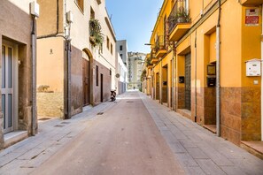 A narrow street lined with buildings, some with balconies and plants. - Why do we call this stylish beach loft dreamy? (Barcelona)