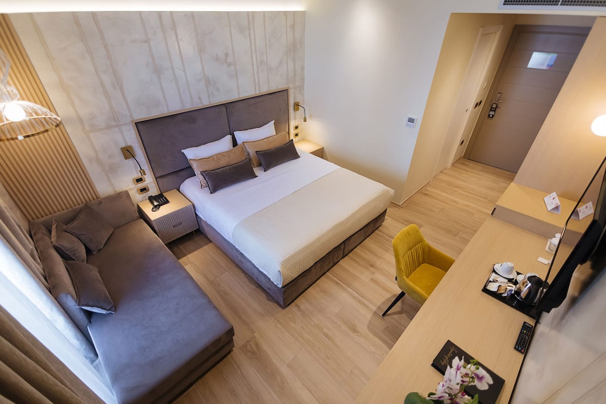 Una habitación de hotel moderna con una cama grande, un sofá, un escritorio y una silla.