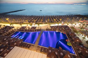 A resort with a large pool area, multiple sun loungers, and a view of the ocean.